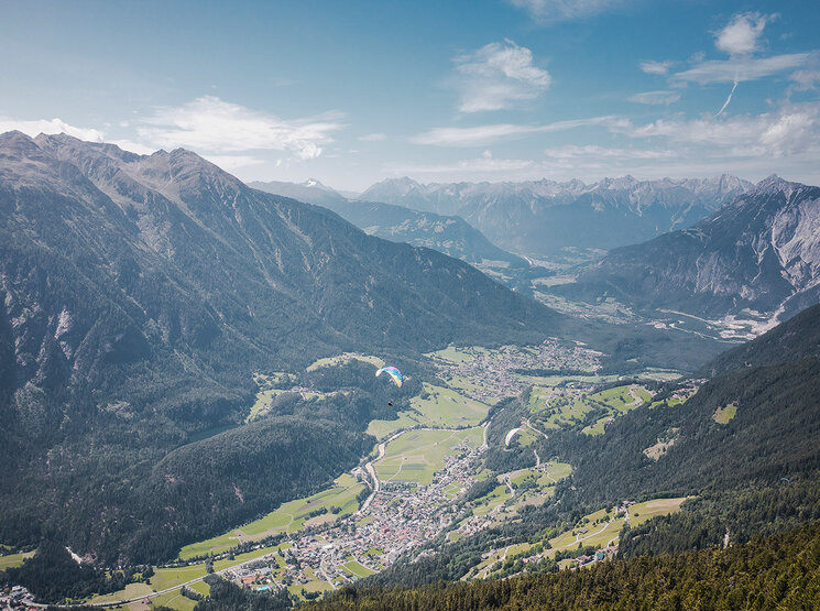 Eine malerische Luftaufnahme, umgeben von üppig grünen Wäldern und hohen Bergen unter einem teilweise bewölkten blauen Himmel.
